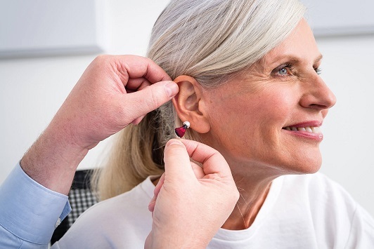 Ältere Frau bekommt ein modernes Hörgerät zur Verbesserung des Hörvermögens angepasst.